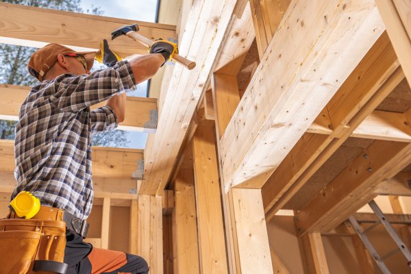 Professional Caucasian Construction Contractor Worker Attaching Wooden Elements to the Structure